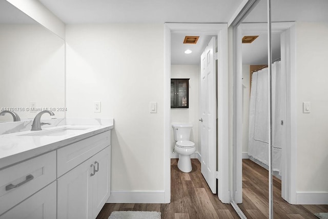 bathroom with wood-type flooring, vanity, and toilet