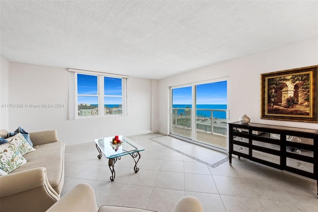 tiled living room featuring a water view, a healthy amount of sunlight, and a textured ceiling