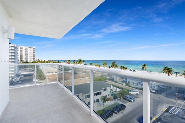 balcony with a water view and a view of the beach