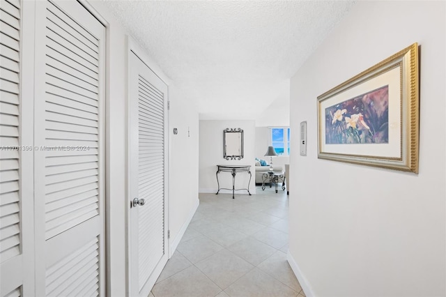 corridor featuring light tile patterned flooring and a textured ceiling