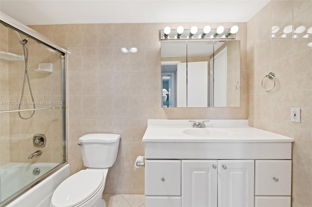 full bathroom with tile patterned floors, vanity, tile walls, enclosed tub / shower combo, and toilet