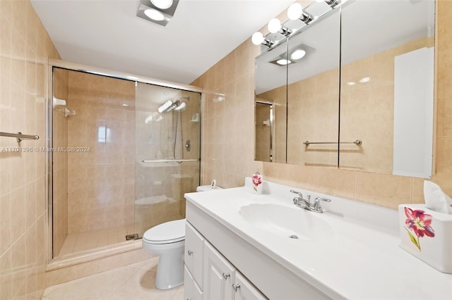 bathroom featuring walk in shower, tile patterned floors, toilet, vanity, and tile walls