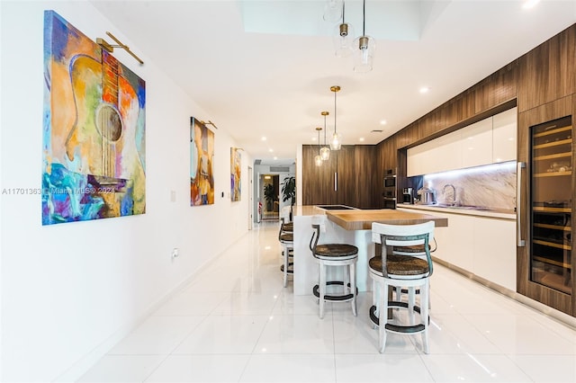 kitchen with decorative light fixtures, a center island, white cabinetry, and wooden walls