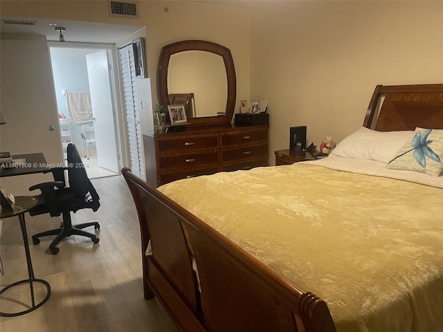 bedroom with hardwood / wood-style floors and ensuite bathroom