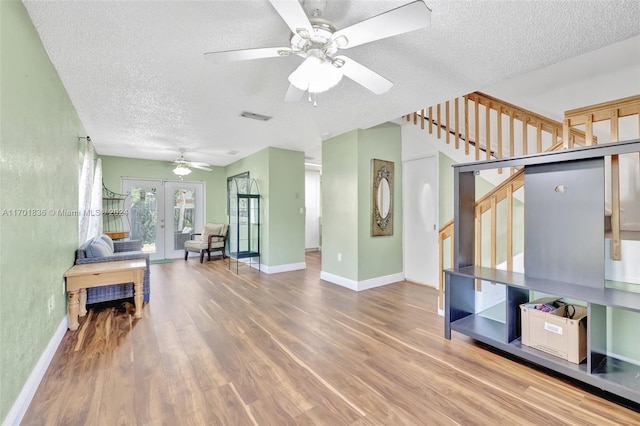 living room featuring ceiling fan, french doors, wood-type flooring, and a textured ceiling