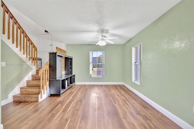 unfurnished living room with ceiling fan, hardwood / wood-style floors, and a textured ceiling