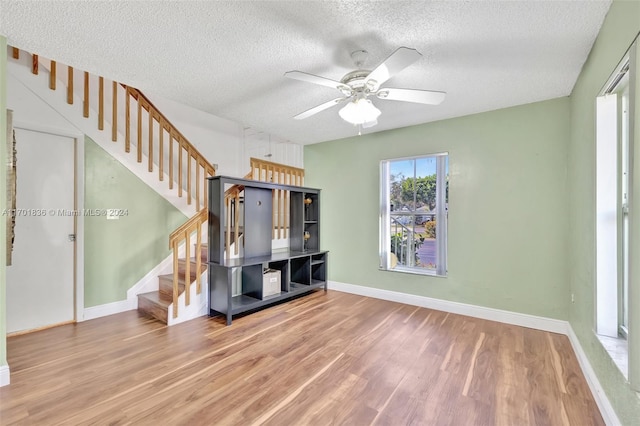 unfurnished living room with a textured ceiling, hardwood / wood-style flooring, and ceiling fan