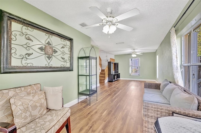 living room with hardwood / wood-style floors, ceiling fan, and a textured ceiling