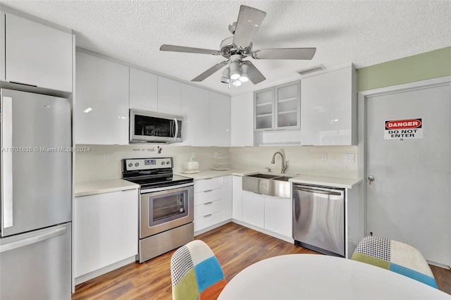 kitchen with white cabinets, light wood-type flooring, and stainless steel appliances