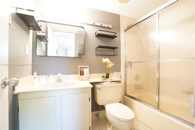 full bathroom with shower / bath combination with glass door, tile patterned flooring, vanity, and toilet