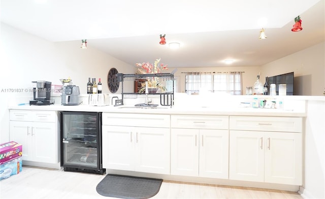 kitchen with sink, white cabinets, and beverage cooler