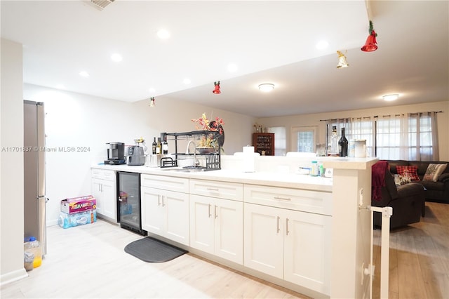 kitchen with sink, wine cooler, stainless steel fridge, light wood-type flooring, and white cabinetry