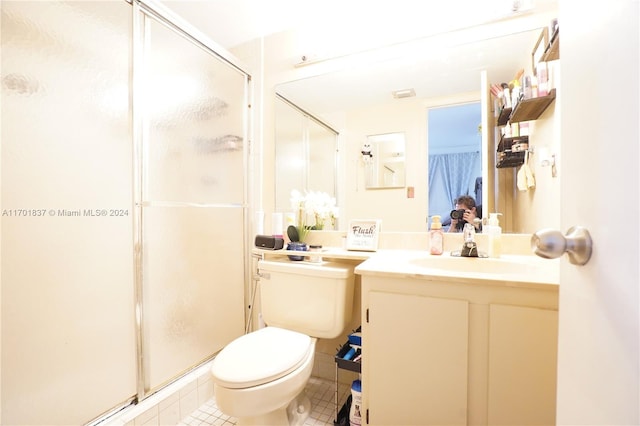 bathroom featuring tile patterned floors, vanity, a shower with shower door, and toilet