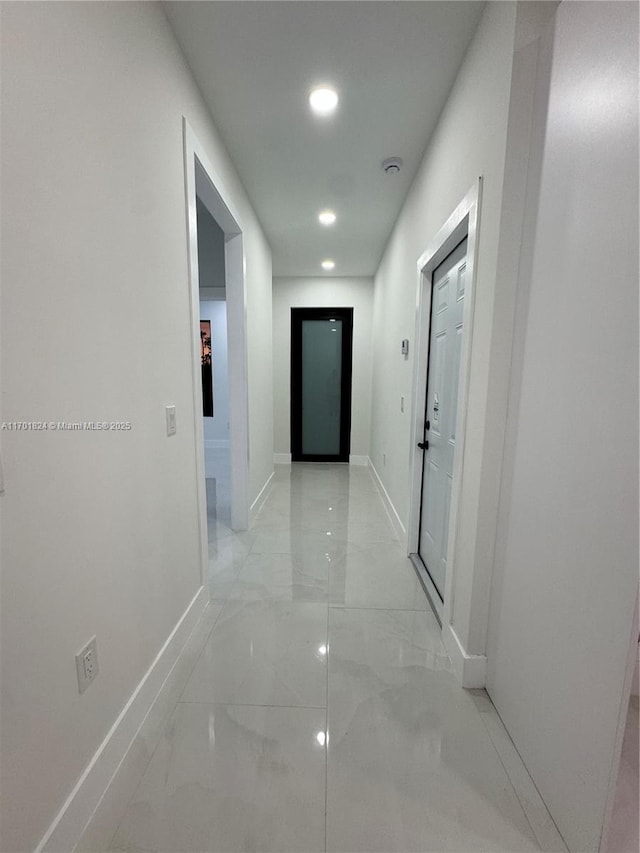 corridor with marble finish floor, baseboards, and recessed lighting