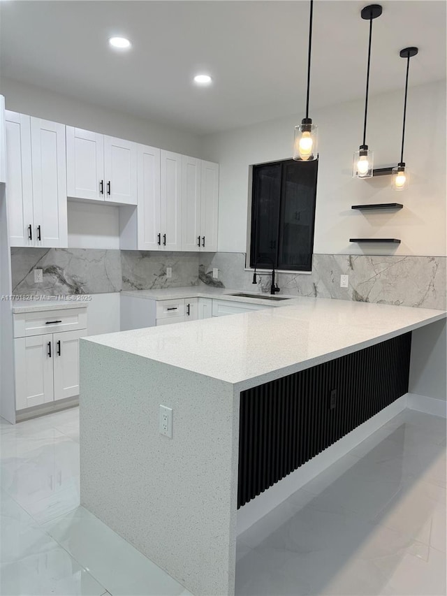 kitchen with tasteful backsplash, a peninsula, marble finish floor, white cabinetry, and recessed lighting