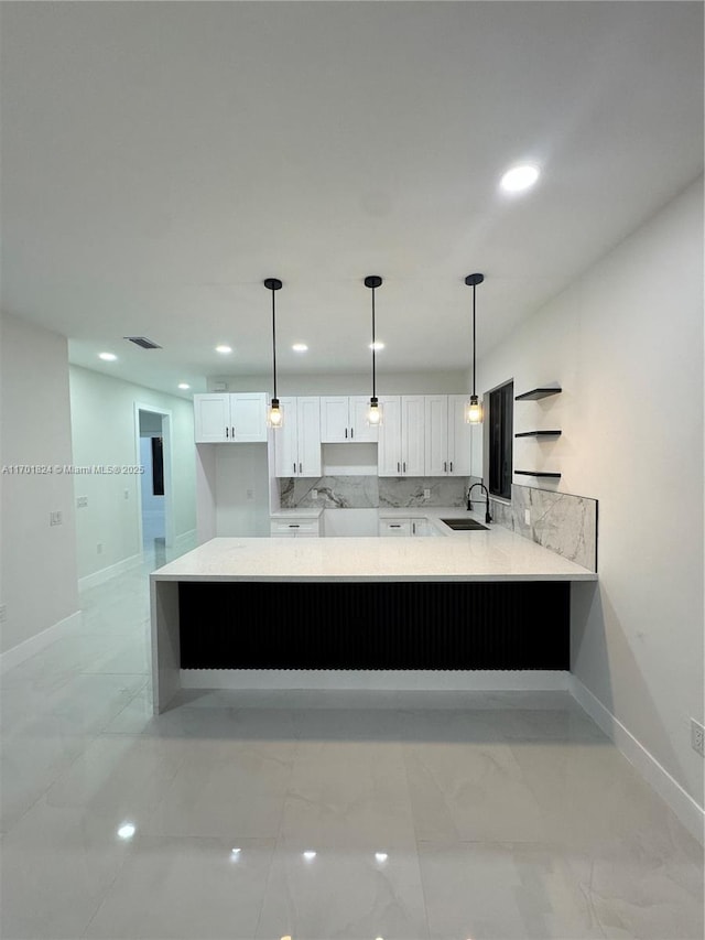 kitchen featuring marble finish floor, visible vents, white cabinetry, a sink, and a peninsula