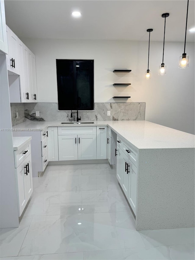 kitchen with marble finish floor, a sink, backsplash, and a peninsula