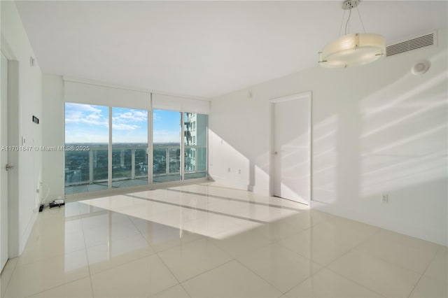 tiled spare room featuring expansive windows