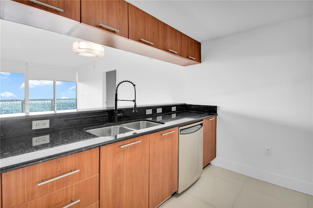 kitchen with sink, light tile patterned floors, stainless steel dishwasher, and dark stone counters