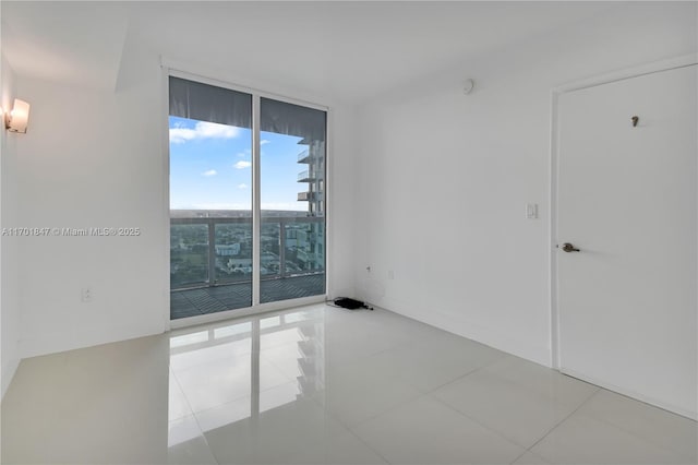 spare room featuring light tile patterned floors and expansive windows