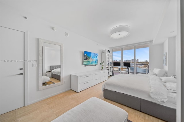 bedroom with light hardwood / wood-style floors and a wall of windows