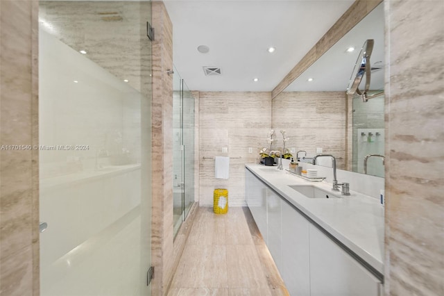 bathroom with hardwood / wood-style floors, vanity, a shower with door, and tile walls