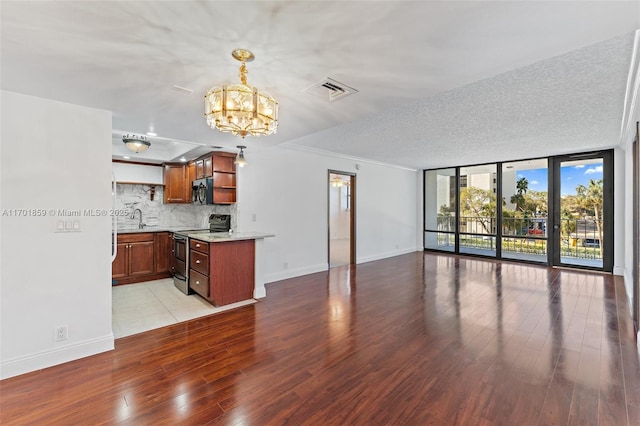 kitchen featuring kitchen peninsula, appliances with stainless steel finishes, backsplash, pendant lighting, and expansive windows