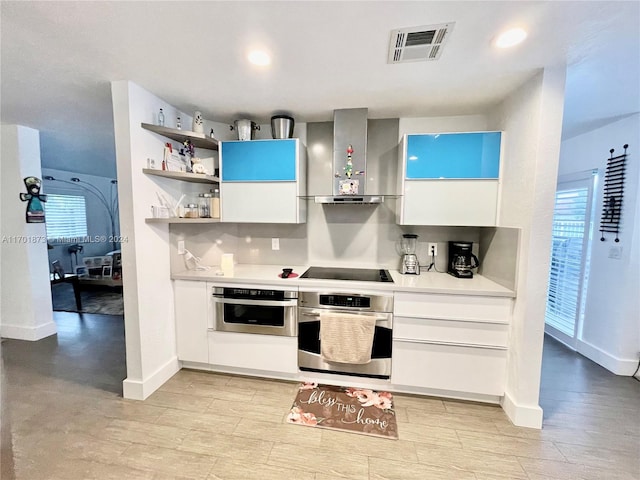 kitchen featuring oven, white cabinetry, wall chimney range hood, and black electric cooktop