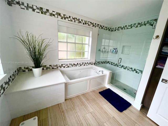 bathroom with tile walls and shower with separate bathtub