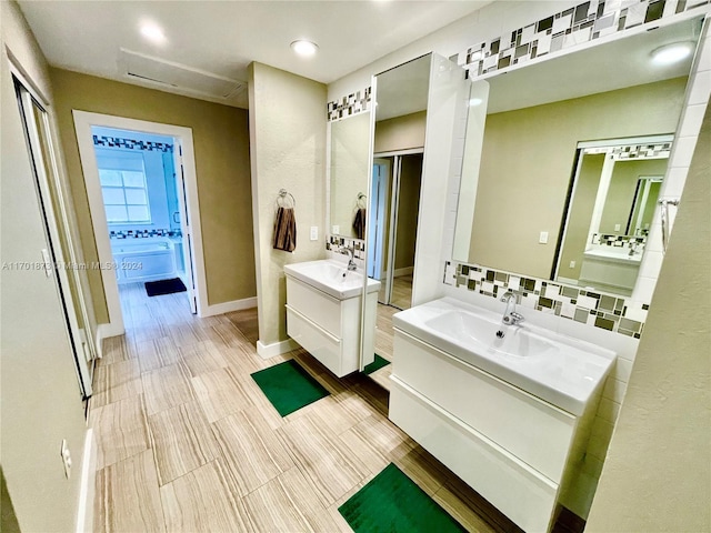 bathroom with hardwood / wood-style floors, decorative backsplash, a bath, and vanity