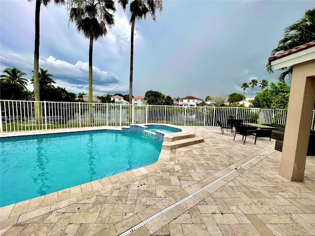 view of pool featuring a patio area, an in ground hot tub, and a water view