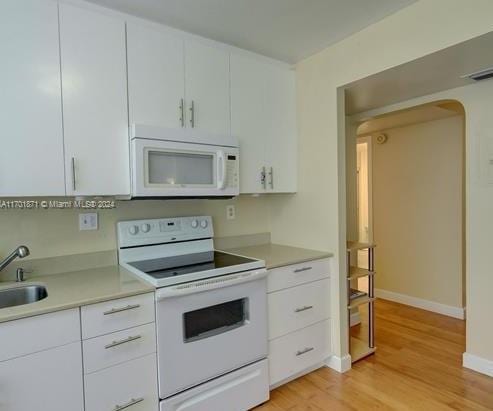 kitchen featuring white appliances, light hardwood / wood-style flooring, white cabinetry, and sink