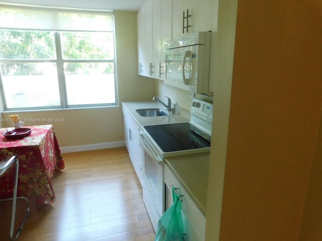 kitchen with white electric stove, white cabinetry, a healthy amount of sunlight, and sink