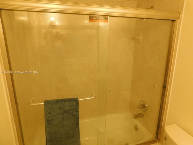 bathroom with toilet and combined bath / shower with glass door