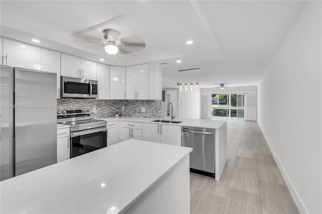 kitchen with pendant lighting, white cabinets, sink, appliances with stainless steel finishes, and kitchen peninsula