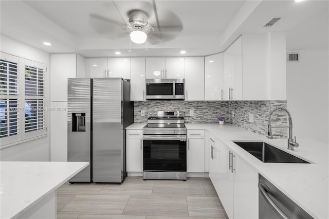 kitchen with ceiling fan, sink, stainless steel appliances, decorative backsplash, and white cabinets