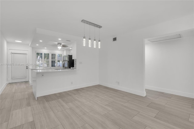 unfurnished living room featuring ceiling fan and sink