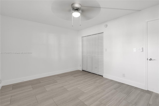 unfurnished bedroom with ceiling fan and a closet