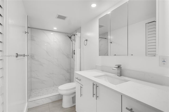 bathroom featuring tiled shower, vanity, and toilet