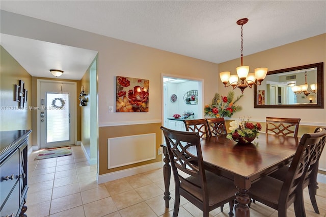 dining space with a chandelier, light tile patterned floors, and a textured ceiling