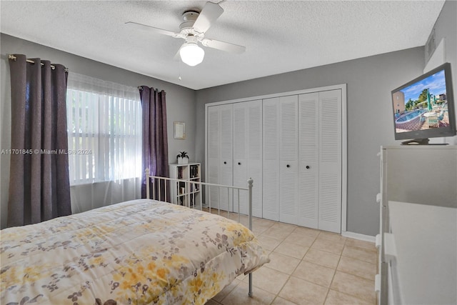 tiled bedroom featuring ceiling fan, a textured ceiling, and a closet