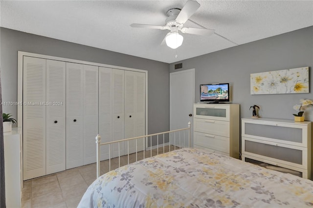 bedroom with light tile patterned floors, a textured ceiling, a closet, and ceiling fan