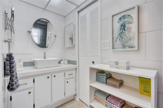 bathroom with tile patterned floors, a drop ceiling, and vanity