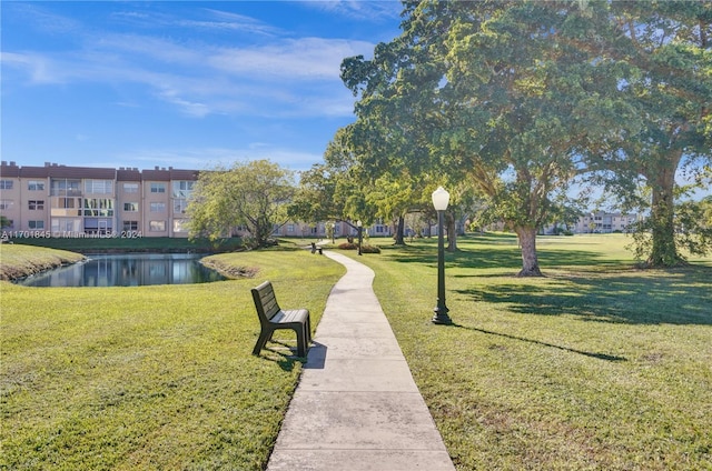 surrounding community with a water view and a lawn