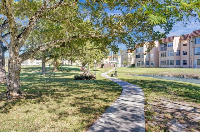 view of property's community with a lawn and a water view