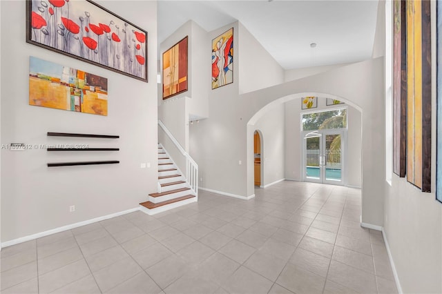 entryway with french doors, light tile patterned floors, and high vaulted ceiling