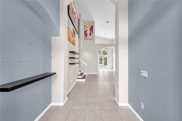 corridor featuring light tile patterned floors and lofted ceiling