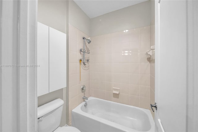 bathroom featuring toilet and tiled shower / bath