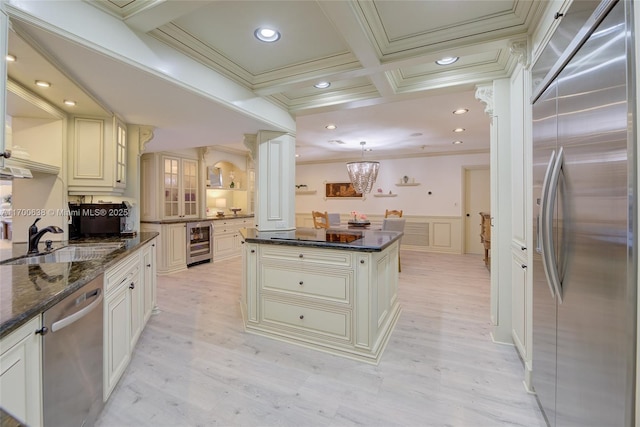 kitchen featuring sink, decorative light fixtures, a center island, stainless steel appliances, and beverage cooler