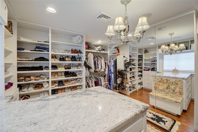 walk in closet with an inviting chandelier and light wood-type flooring